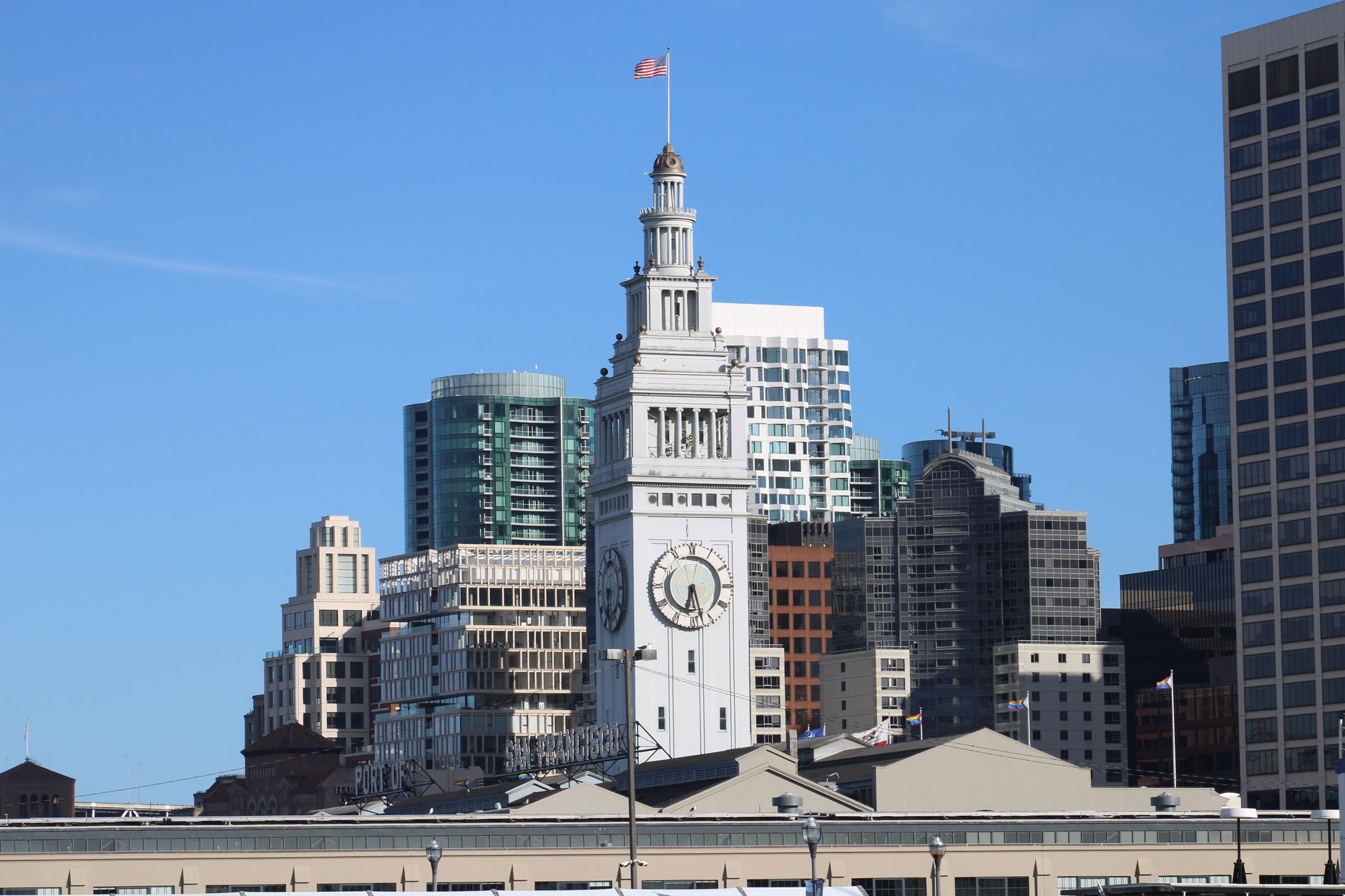 San Francisco's Ferry Building with urban skyscraper backdrop under a clear blue sky.